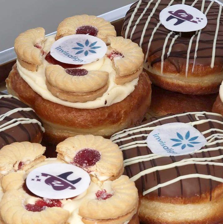 Close up of branded corporate doughnuts with logos including Invisalign and Smile 'n' Shine