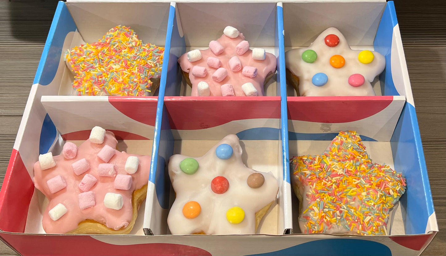 A box of mini star shaped doughnuts with colourful sprinkles and smarties on top