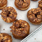 Donuts with chocolate glaze and pecan toppings on a baking tray.