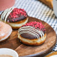 Donuts with chocolate glaze and red sprinkles on a wooden board.