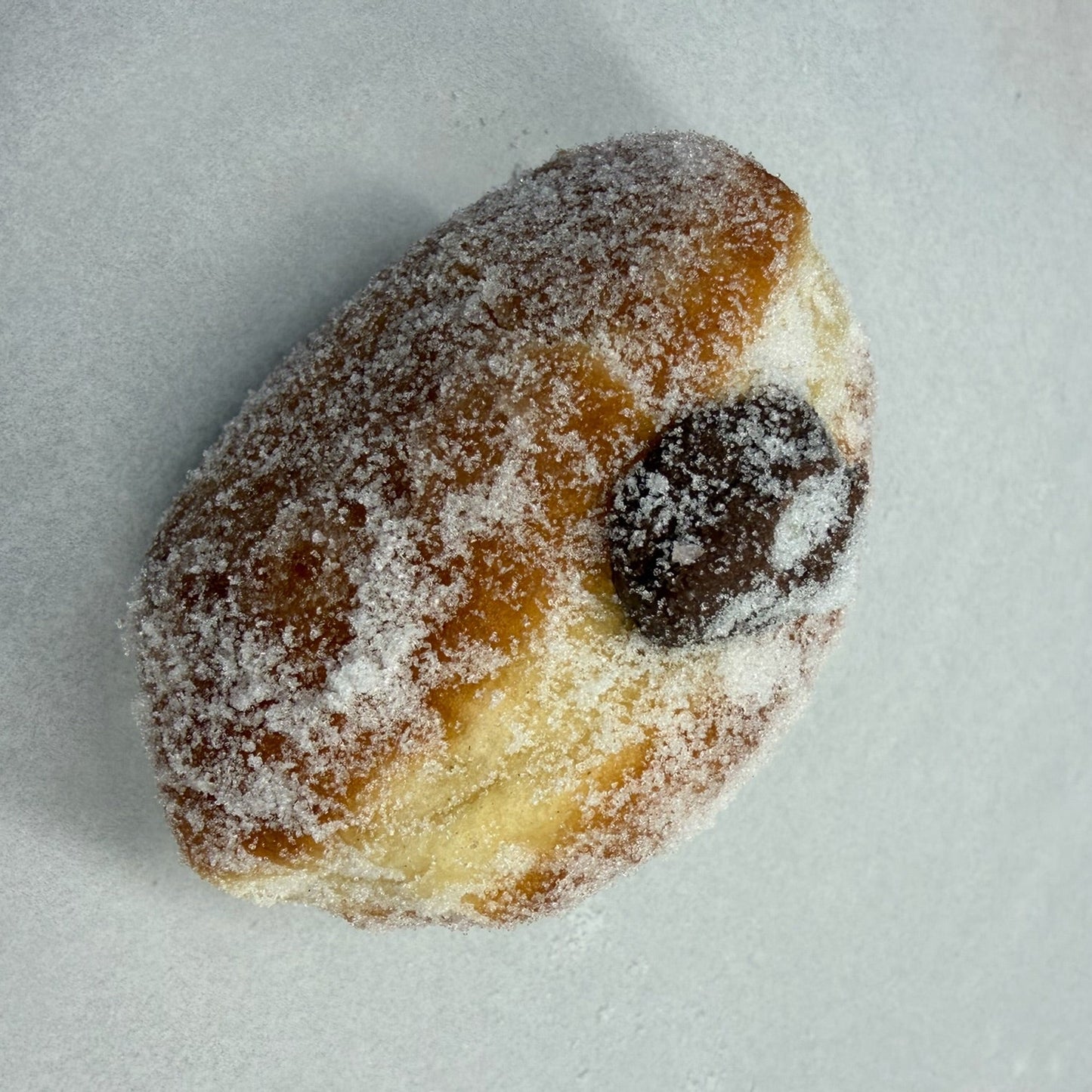 A doughnut dusted with sugar and filled with Nutella.