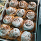 Metal tray with cinnamon rolls topped with white frosting and cinnamon sprinkles.