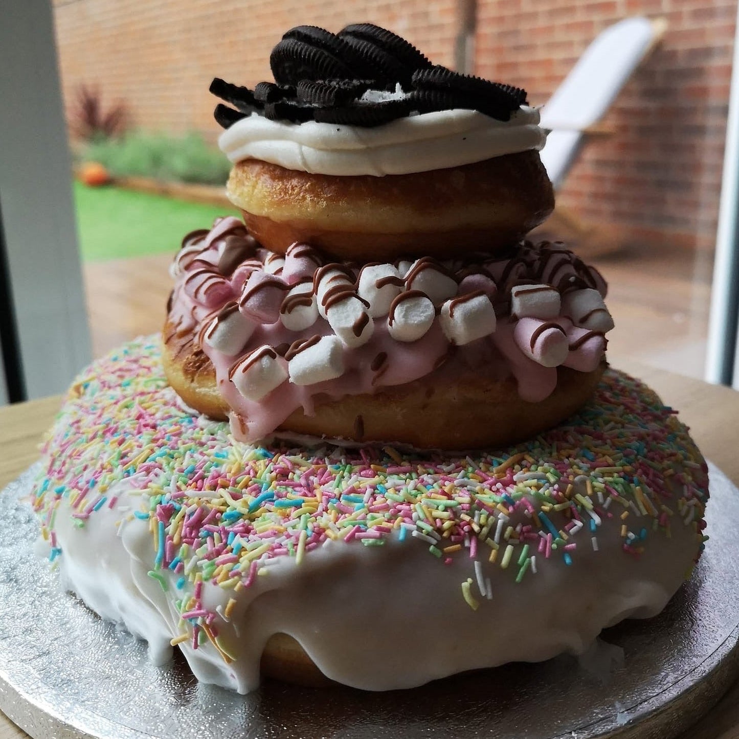 A large cake made of doughnuts with sprinkles, biscuits and marshmallows