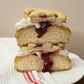 A jam biscuit doughnut cut in half so you can see the jam oozing out and biscuits on top
