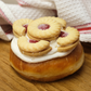 A single doughnut with white icing topped with jam biscuits