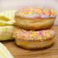 A stack of two ring doughnuts topped with colourful sprinkles